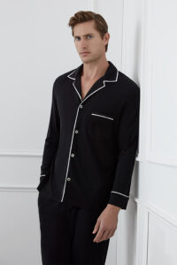A man wearing a  black MANITO Jersey Men's Modal Silk Pajama Set with white piping.